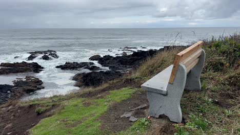 empty bench facing rocky beach on a cloudy day in oregon