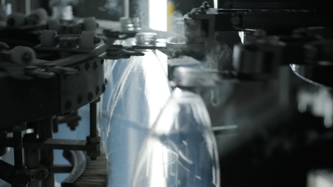 Automatic filling machine pours water into plastic PET bottles at modern beverage plant