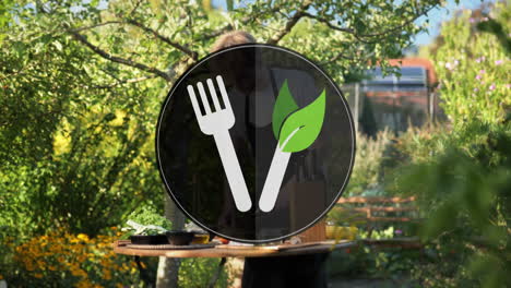 digital symbol fork and leaf knife for conscious vegan diet in front of cooking area with male chef in outdoor kitchen on sunny day