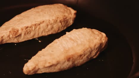 filetes de pollo veganos chisporroteando en aceite en una sartén caliente
