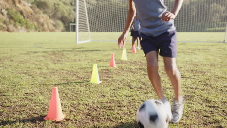 running soccer drills, kids practicing on field with cones and goal in school
