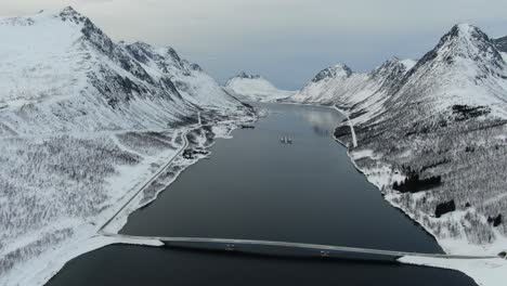 vista del avión no tripulado en el área de tromso en invierno volando sobre un fiordo rodeado de montañas blancas en noruega