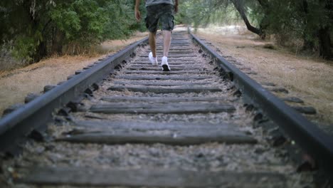 slow motion shot of a lonely man walking on abandoned train tracks