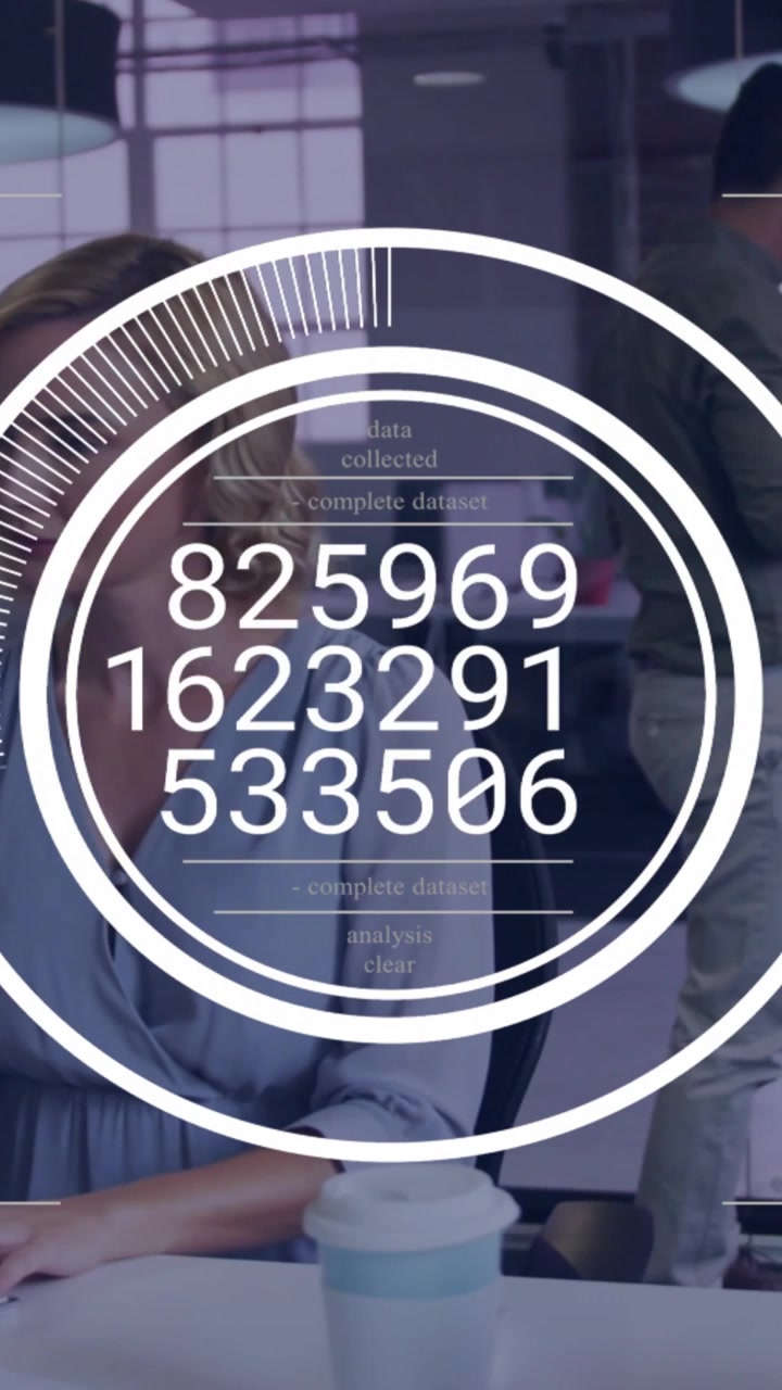 Vertical video: Woman typing at desk in tech office, HUD popping up, dial updating data then fading