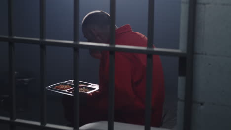 close up of prisoner in orange uniform holding metal bars in prison cell          (stock footage)