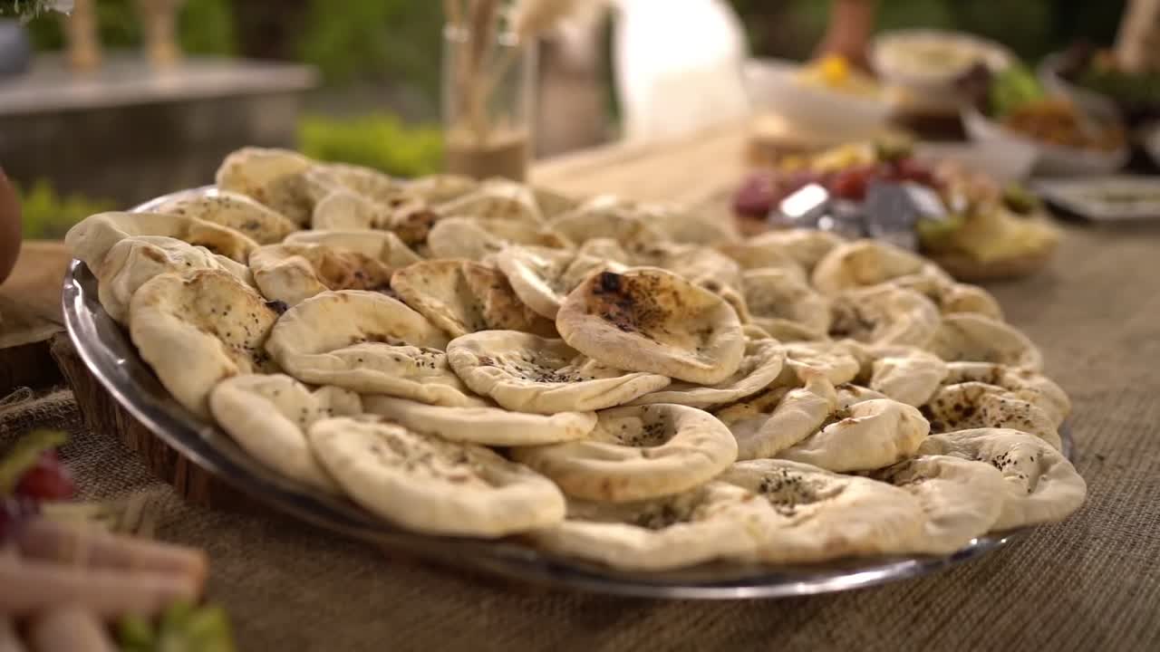 A large tray of mini flatbreads served on a rustic outdoor table for a festive meal, close up shot