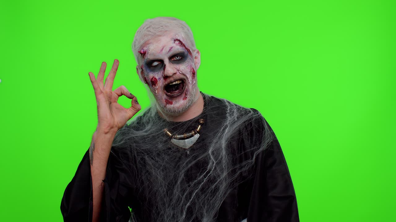 Uomo inquietante in versione zombie di Halloween che fa il gesto "Ok", come un segno positivo o di approvazione, e sorride in modo terrificante.