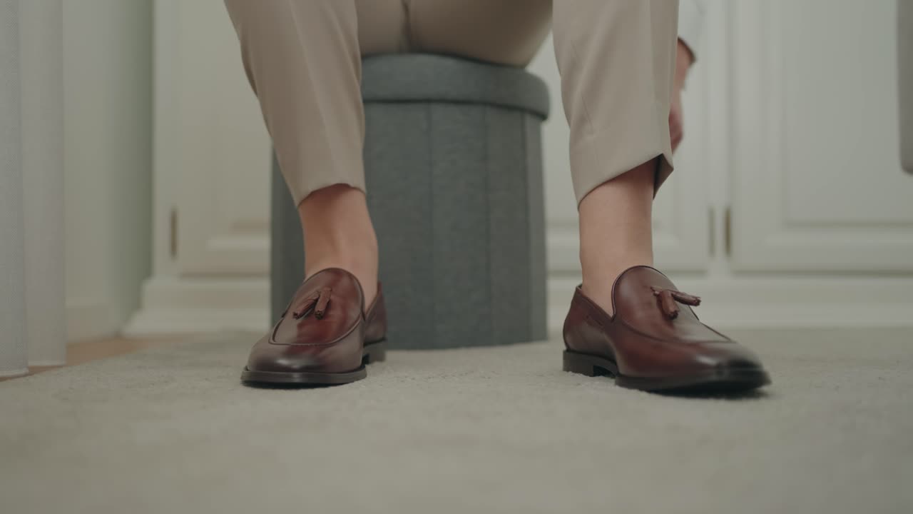 Unos mocasines marrones que se calzan cuidadosamente en una habitación tranquila y luminosa