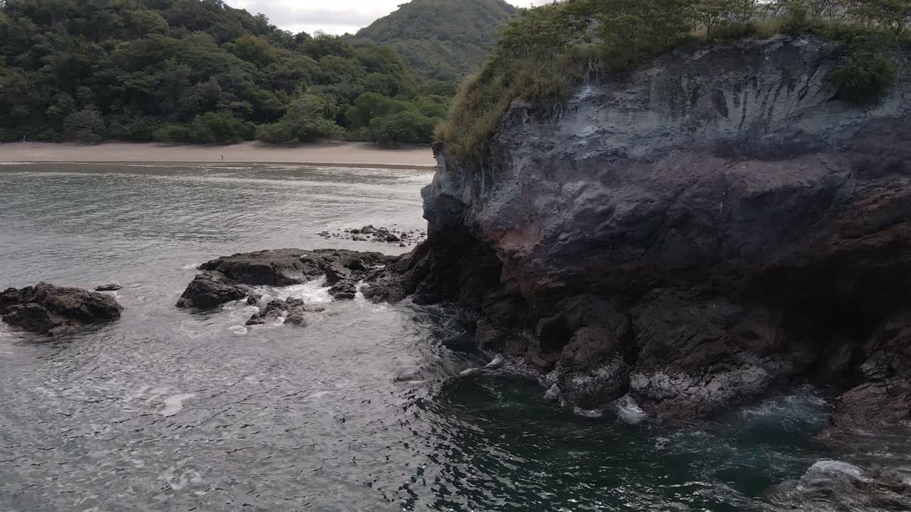 rotación lenta alrededor de una gran pared rocosa que revela una hermosa playa y costa en playa real en la provincia de guanacaste