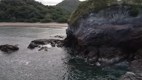 Rotación-Lenta-Alrededor-De-Una-Gran-Pared-Rocosa-Que-Revela-Una-Hermosa-Playa-Y-Costa-En-Playa-Real-En-La-Provincia-De-Guanacaste