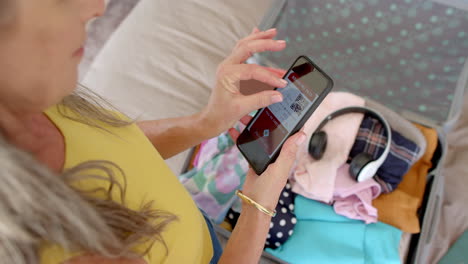 A-mature-Caucasian-woman-holding-smartphone-with-a-boarding-pass-on-screen