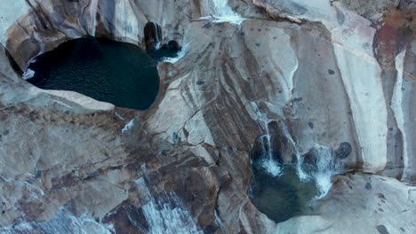 top down aerial shot of cascading waterfalls and pools on a granite rock face