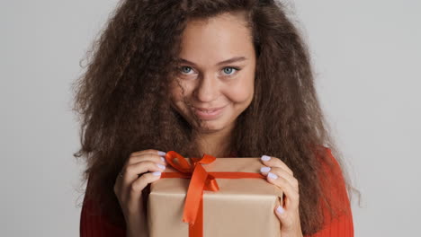 happy caucasian curly haired woman with a present.