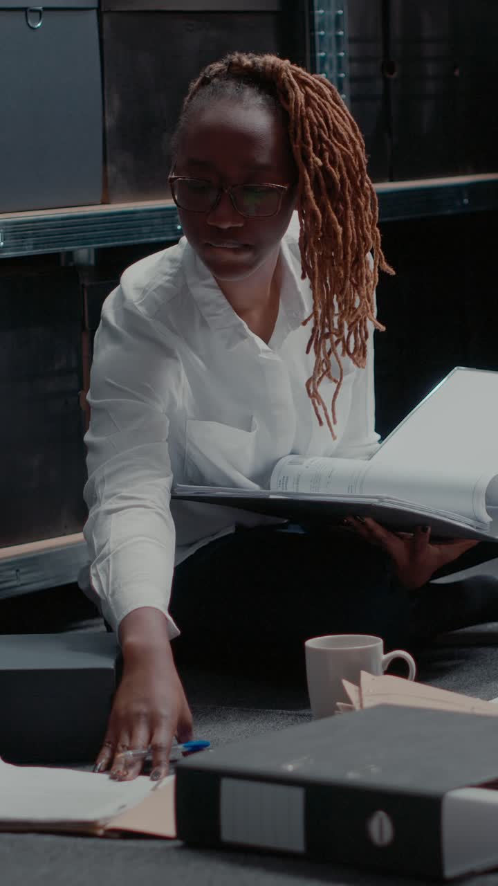 Vertical video: Focused law officer examining case files in folder