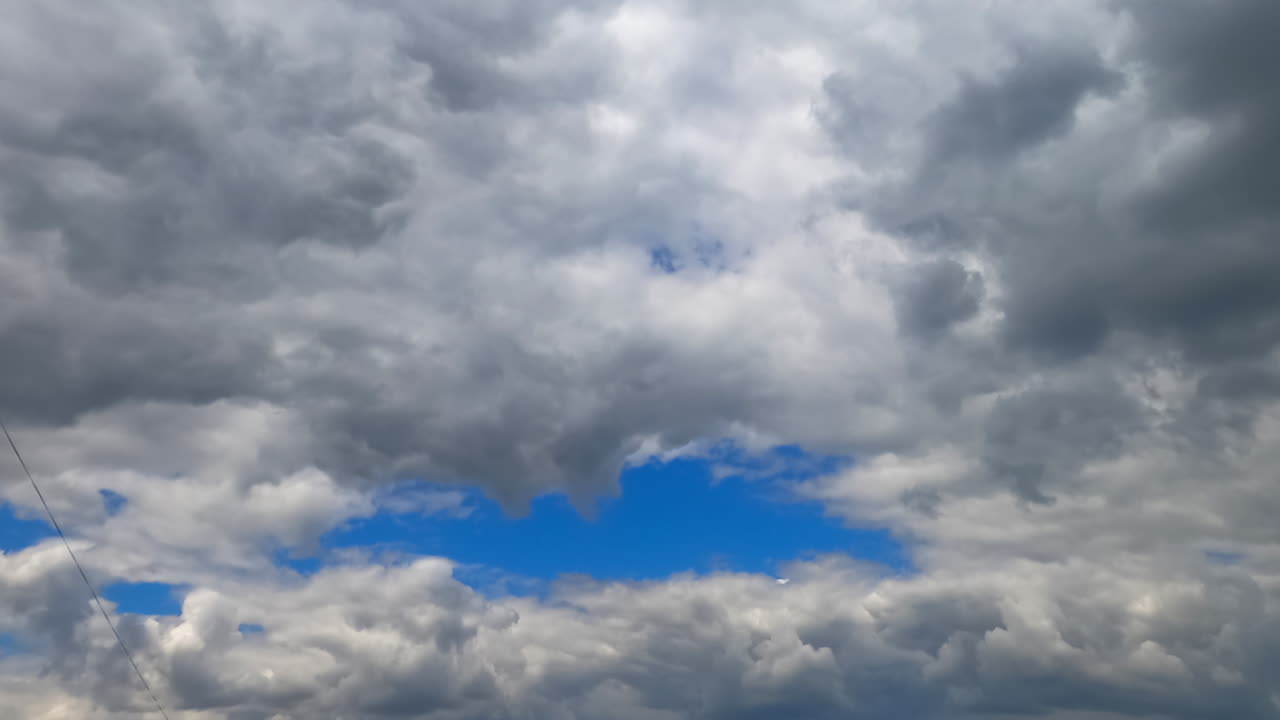 Multiple clouds accumulate in the atmosphere. Low angle view on the grey cloudscape gathering in the sky. Timelapse.