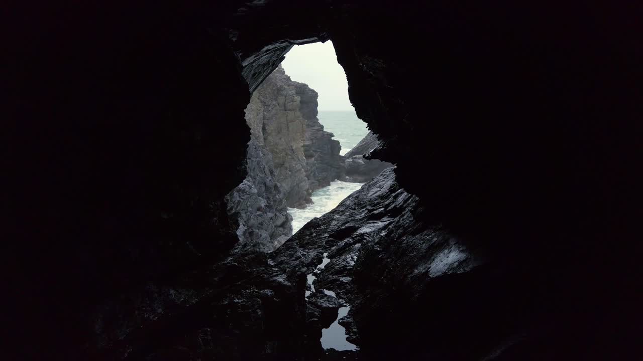 코른월 크랜 (cornwall crantock) 은 동굴 창문을 통해 거친 바다와 바위의 광경입니다.