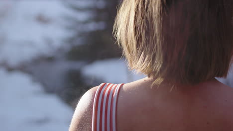 steaming hot skin of woman stepping out of sauna into snowy outdoors, rear view
