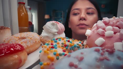 woman looking into a refrigerator full of colorful donuts and other sugary treats