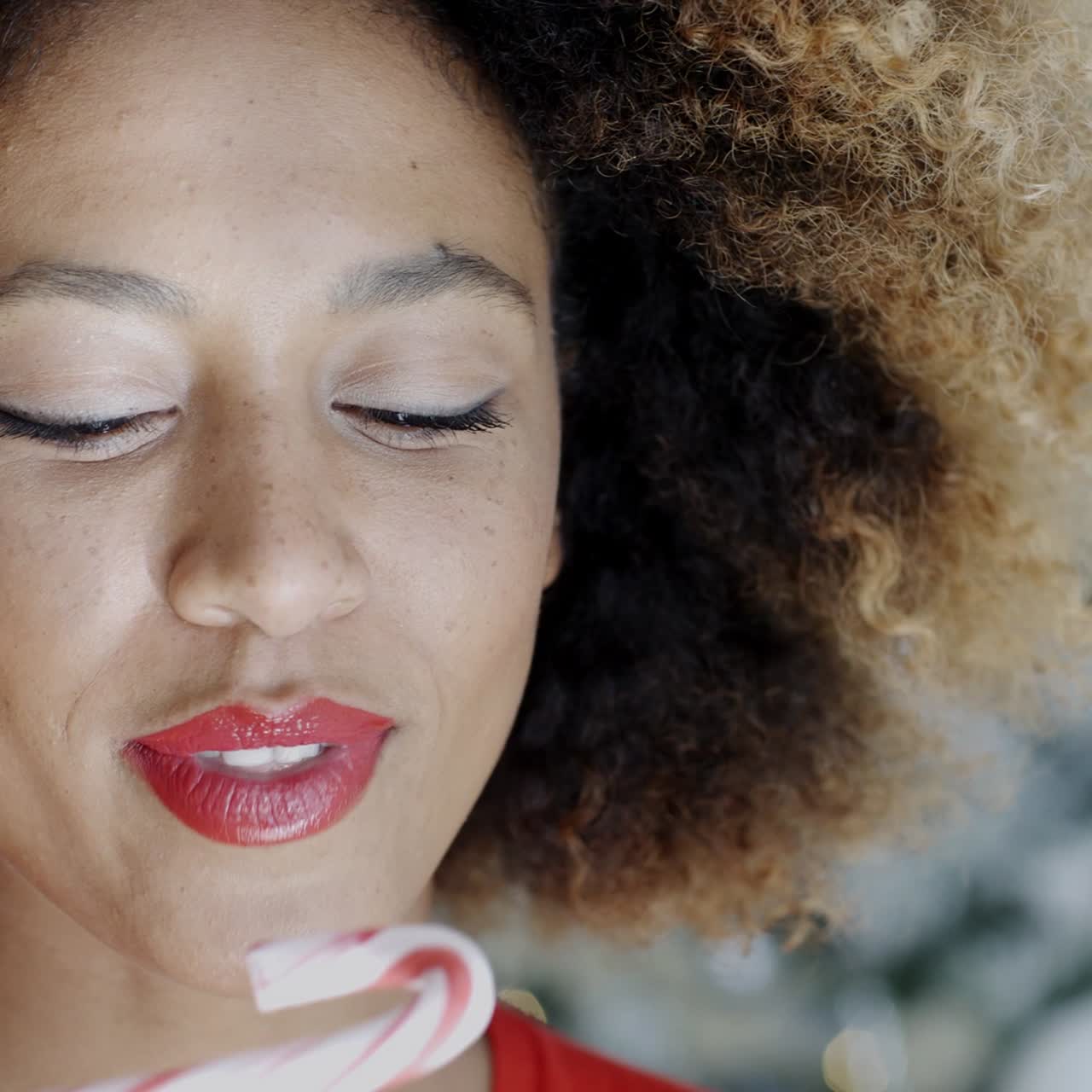 mujer joven mordiendo un bastón de caramelo festivo