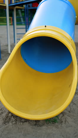 lovely child appears from the tunnel slide. smiling kid stands on his feet and runs to slide again. vertical video.