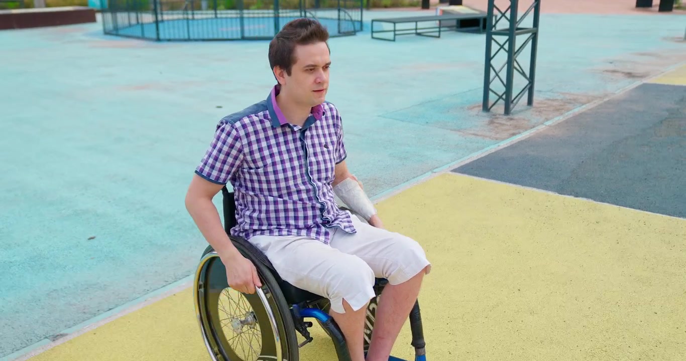 Jovem com Braço Engessado Movendo Cadeira de Rodas no Parque