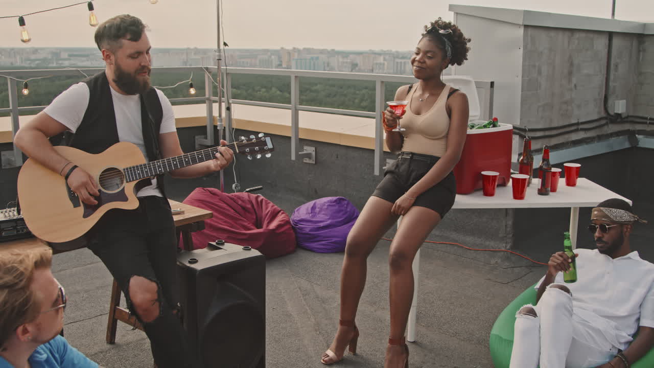 Man Playing Song to Friends on Rooftop Terrace