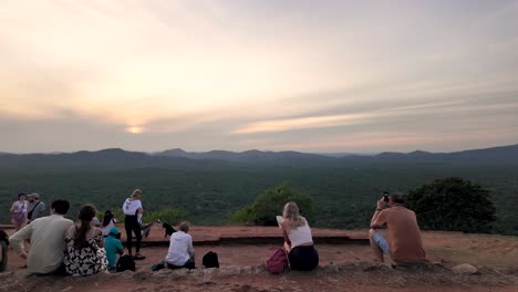 a group of tourists enjoy the breathtaking sunrise view from sigiriya lion rock, capturing the serene landscape of sri lanka.