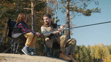 Father and son fishing in autumn forest