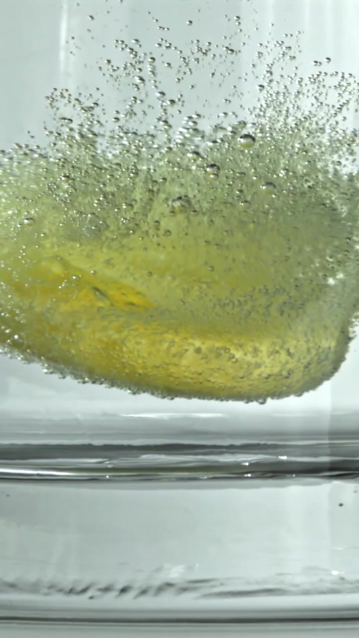 Primo piano di una compressa effervescente che si dissolve in un bicchiere d'acqua con bollicine