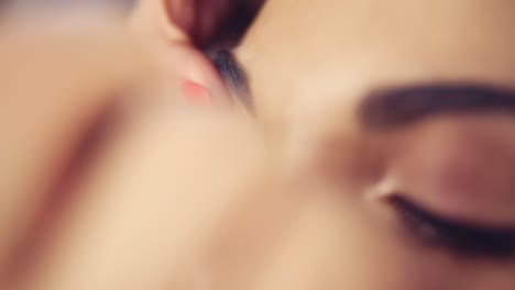 close up view of professional makeup artist applying mascara on the model's eyelashes. work in beauty fashion industry. backstage