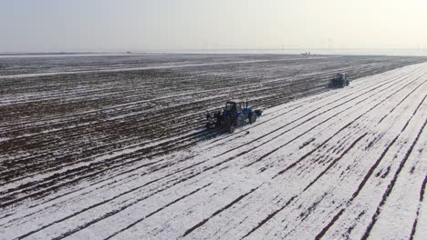 tractors cultivating and seeding the farmland during winter