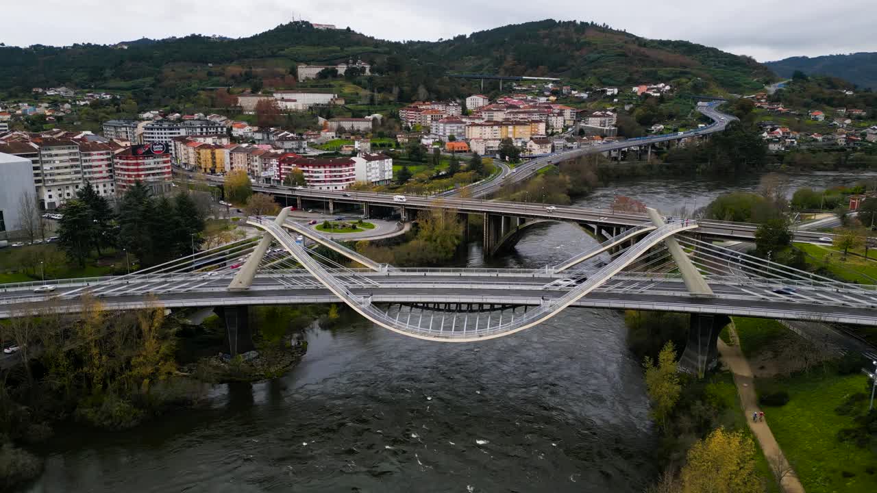 Slow trucking pan around unique curved architecture of Millennium Bridge Mi&ntilde;o River in Ourense, Galicia, Spain