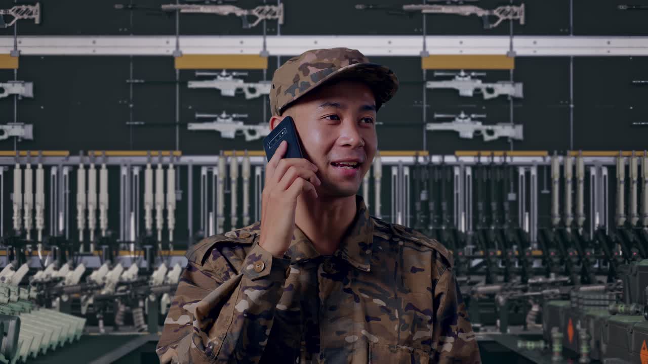 Primo piano di un soldato asiatico che parla al telefono e si guarda intorno in un arsenale militare