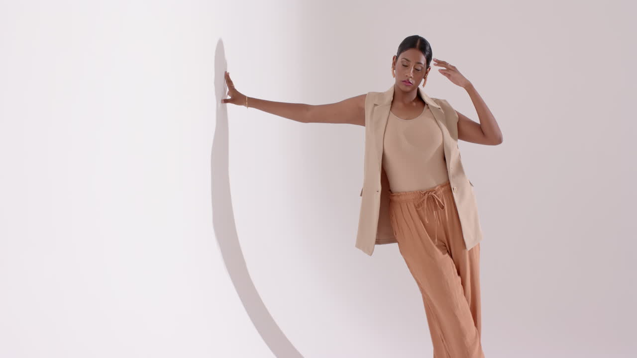 Entering studio Indian female model approaching circular prop placing hand on edge modeling poses