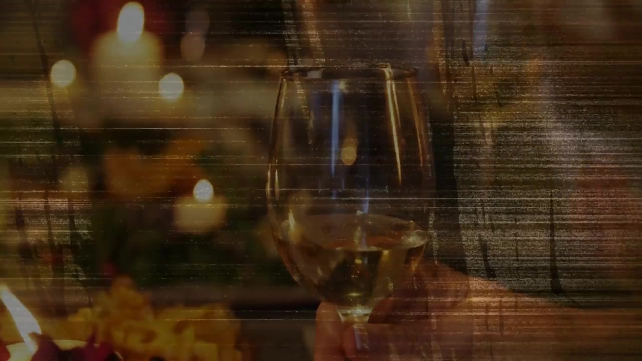 Mão direita estendida segurando taça de vinho com haste e levantando em direção ao centro para brinde com velas