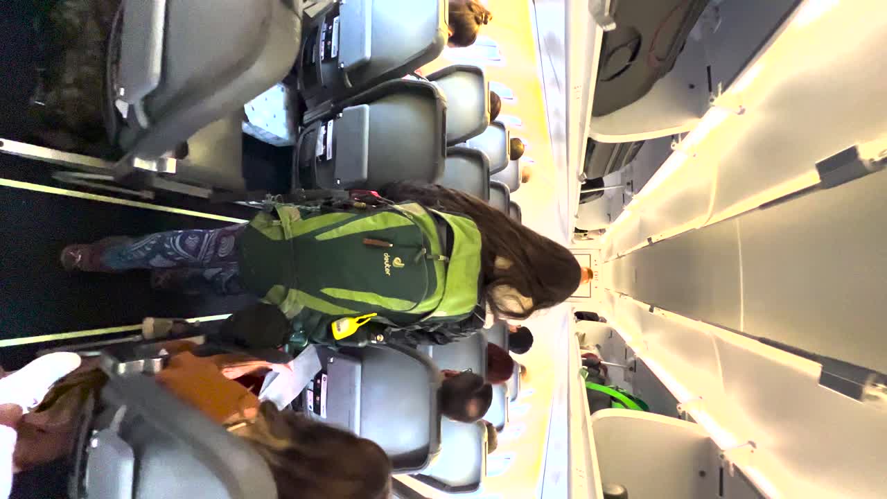 Female passenger with backpack walking down the aisle in an aircraft, backpacker boarding a plane