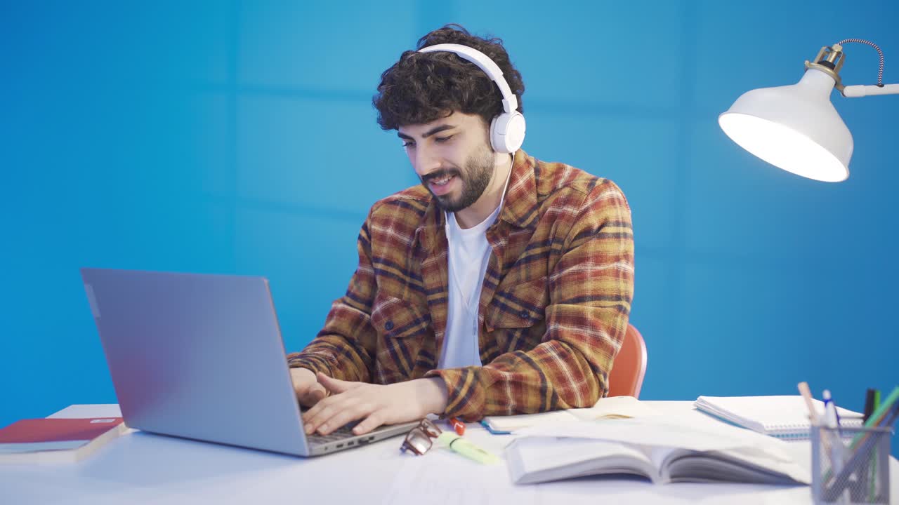 estudiante masculino enfocado usando una computadora portátil buscando información haciendo investigación en línea, escribiendo notas en la computadora.