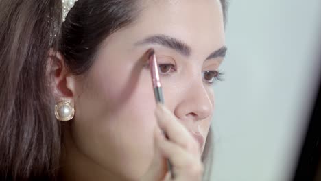 model using brush to gently blend and layer the color onto her eyelids