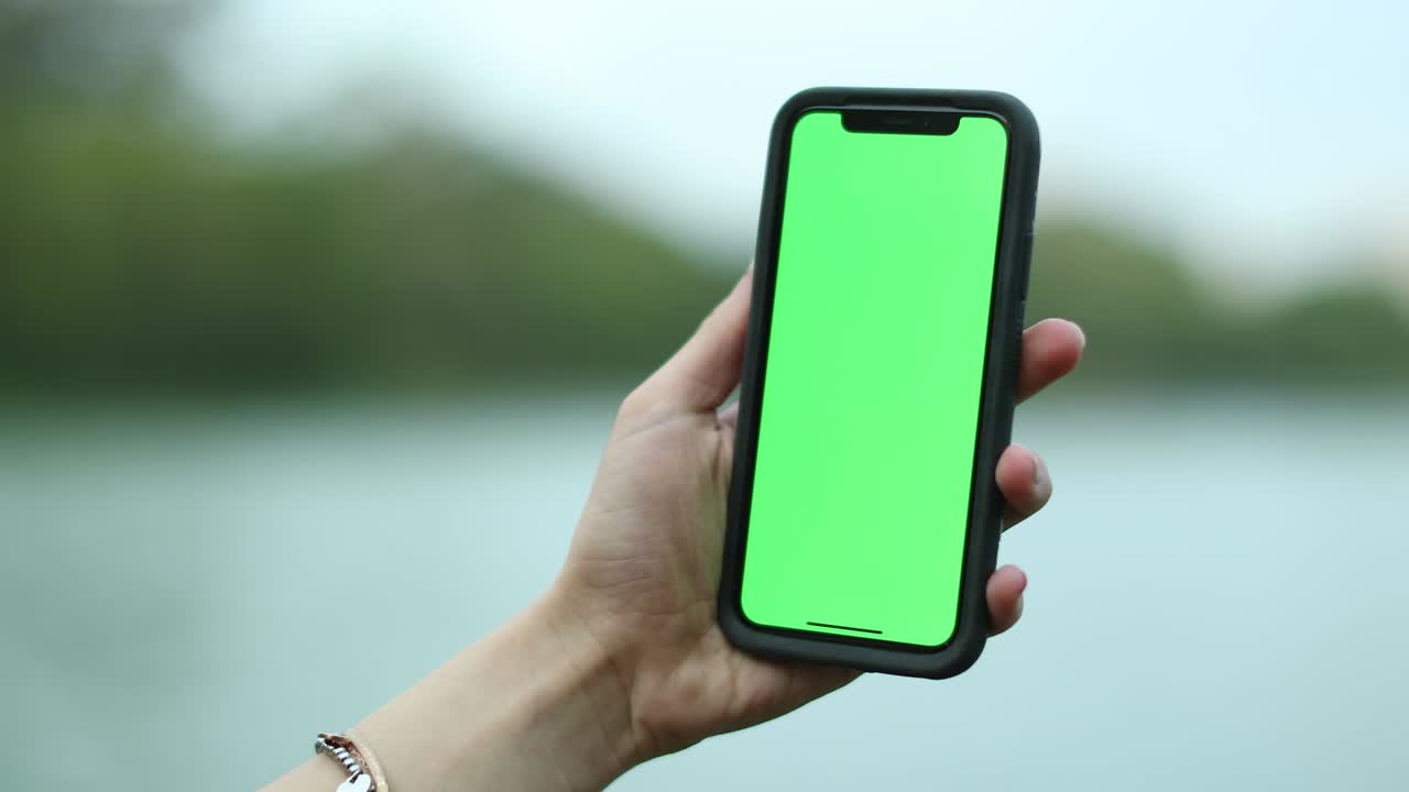 mujer con la mano sosteniendo un teléfono móvil con pantalla verde. niña usando teléfono móvil. llave de croma, cerrar la mano de la mujer sosteniendo el teléfono con pantalla verde vertical.