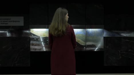 mujer en la estación de metro mirando una instalación de arte