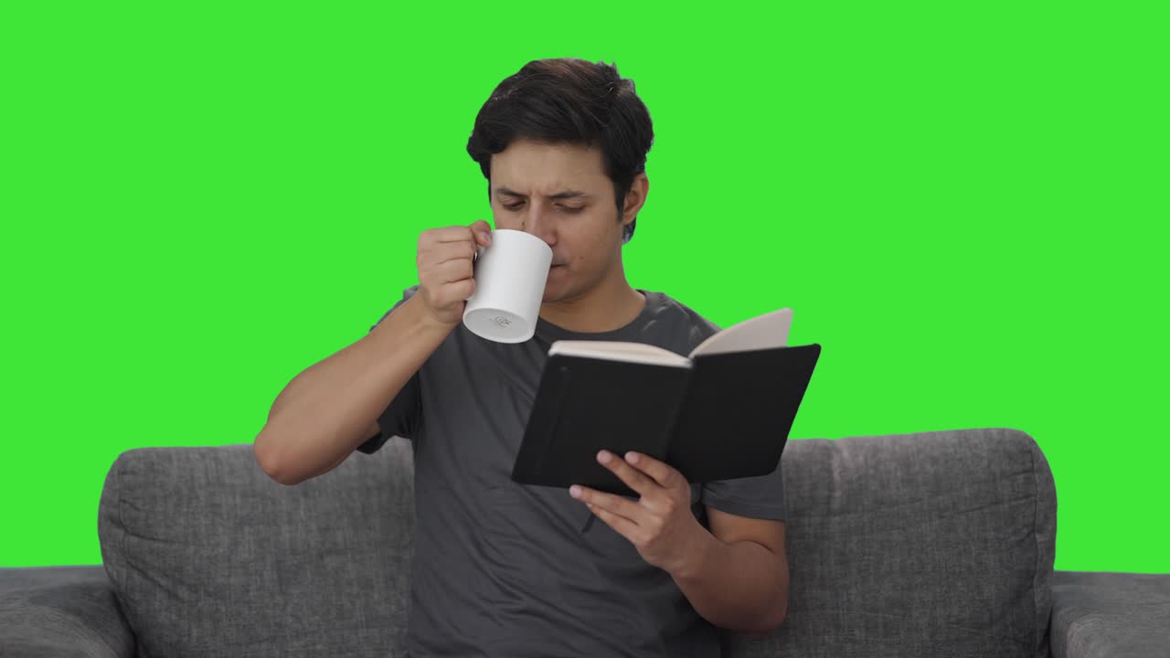 인디언 남자가 책을 읽고 커피를 마시고 녹색 화면