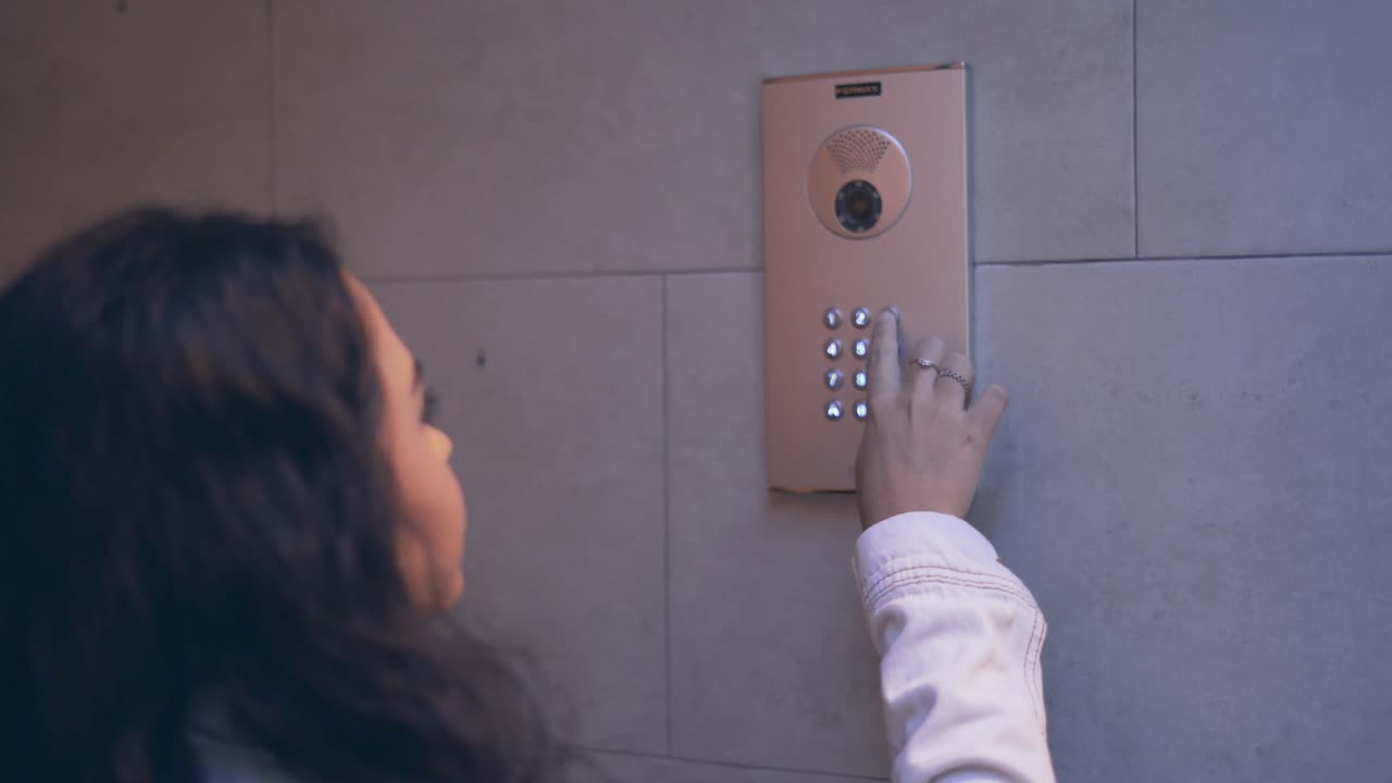 Woman using building intercom keypad
