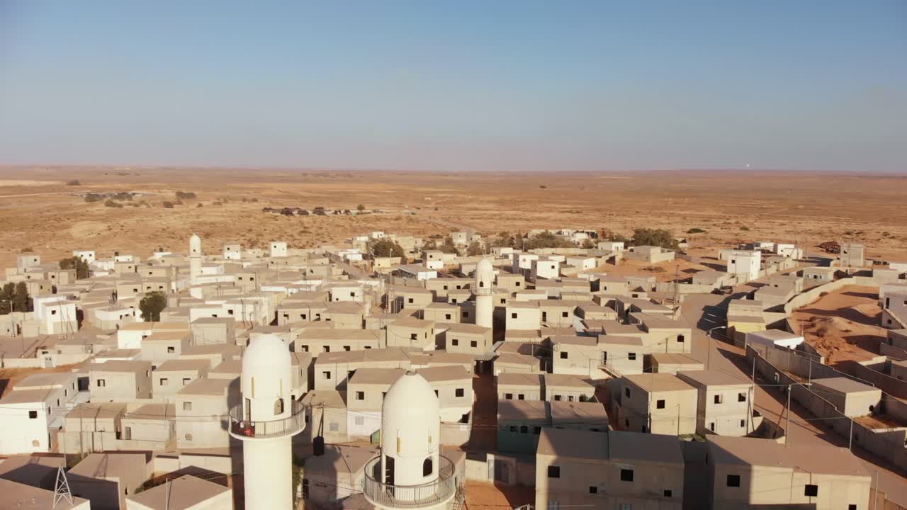 aerial shot of two mosques and some soldiers getting into them in an old empty city in the desert in palestine near Gaza at sunset.