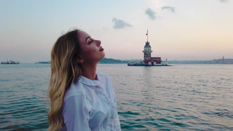 hermosa chica disfruta de la vista del atardecer del bósforo con vista de la torre de la doncella al fondo en estambul