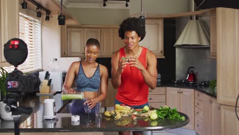 two diverse male and female friends making culinary vlog in kitchen