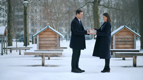 business professionals exchanging a gift in a winter park