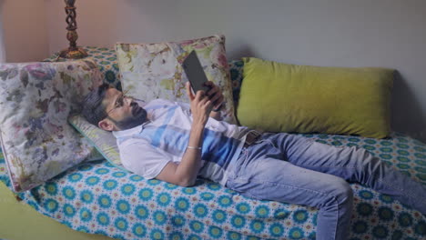 man relaxing on couch using tablet