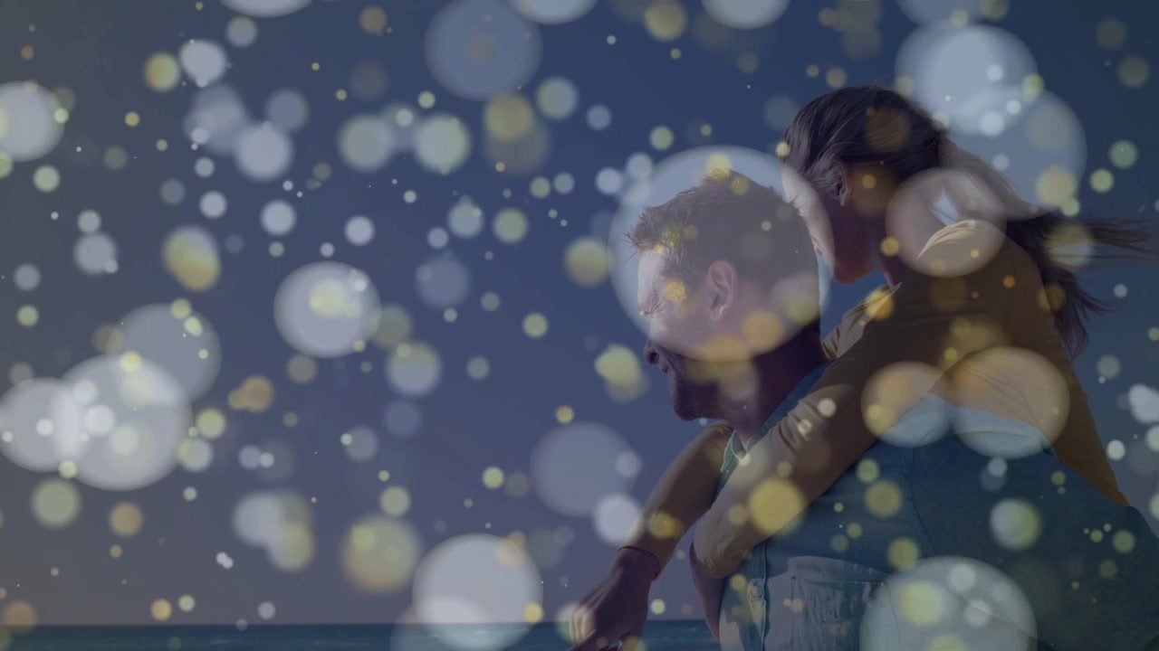 Video verticale: Uomo che porta una donna in spalla sulla riva, indicando e creando un bokeh rotante che offusca il viaggio.