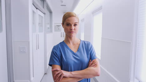 Portrait-Of-Female-Doctor-Wearing-Scrubs-In-Hospital-Corridor