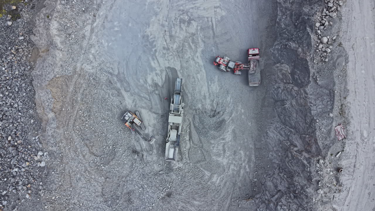 Heavy equipment operates in a mining site as workers manage the extraction process and prepare materials for transport at a construction location in the afternoon